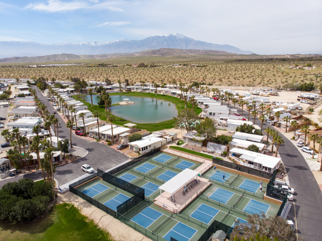 an aerial view of a tennis court surrounded by palm trees
